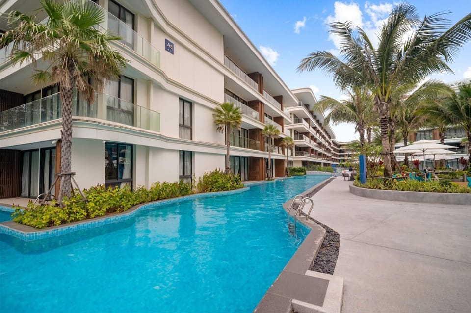 Beautiful lagoon-style swimming pool surrounded by landscaped gardens and modern resort buildings, offering a relaxing outdoor atmosphere.