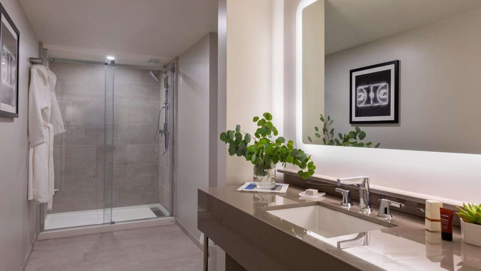 Bathroom with glass shower, wide mirror, and clean counter arrangement.