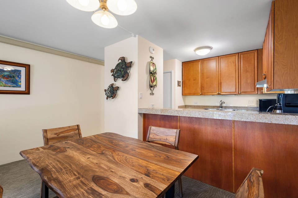 A warm open-plan space blends dining and kitchen with rich wood tones, granite countertops, and thoughtful décor—perfect for sharing meals and making memories together.