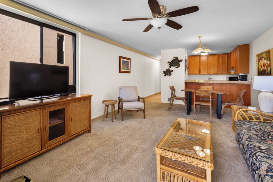 Relax in your open-concept living area, complete with cozy seating, ceiling fan for comfort, entertainment center, dining space, and full kitchen—perfect for unwinding after a day of island adventures.