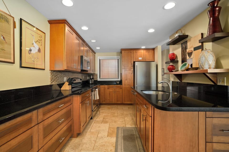 Your fully-equipped kitchen awaits with warm wood cabinets, granite counters, and stainless appliances—perfect for preparing memorable meals during your stay.