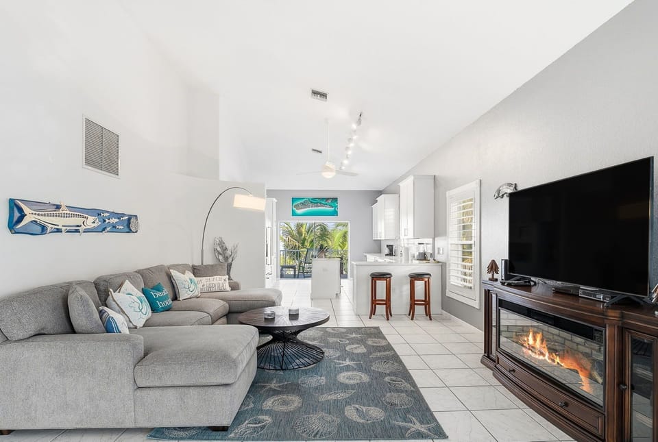 Relax in your bright, open-concept living space with comfortable sectional seating, modern kitchen, and cozy fireplace for the perfect vacation atmosphere.