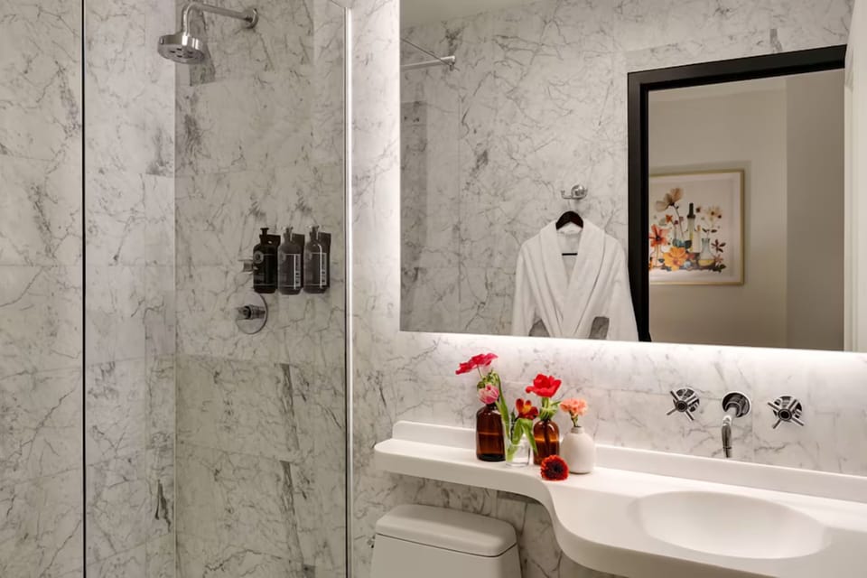 Refresh beneath a rainfall shower and glowing mirror vanity.