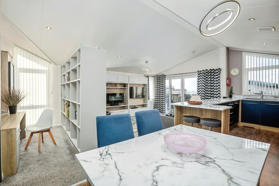 Dining area with table and chairs, view of kitchen, lounge and reading area with desk