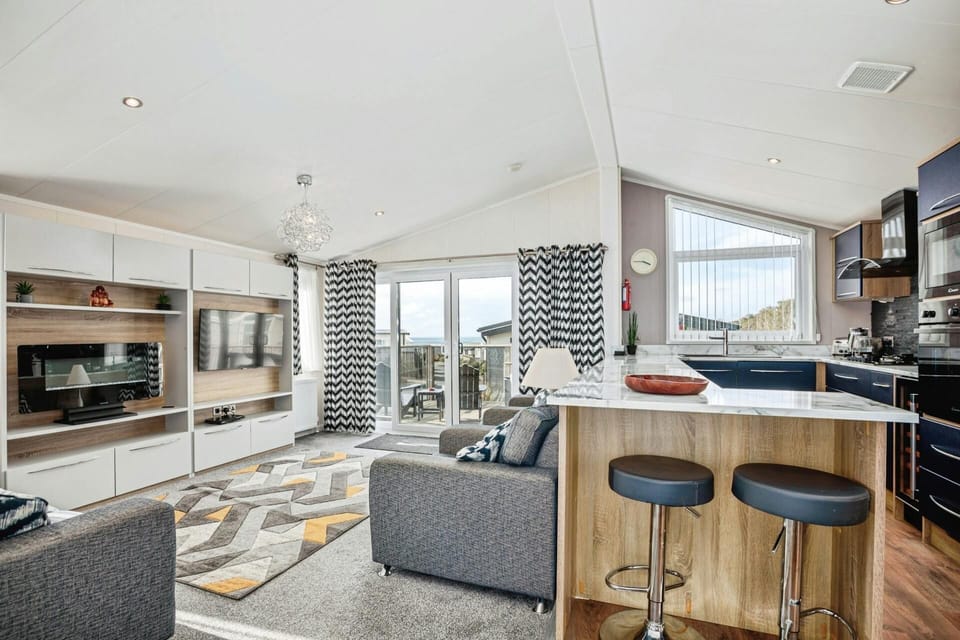 Living area with sofa, armchairs, breakfast bar and stools, kitchen