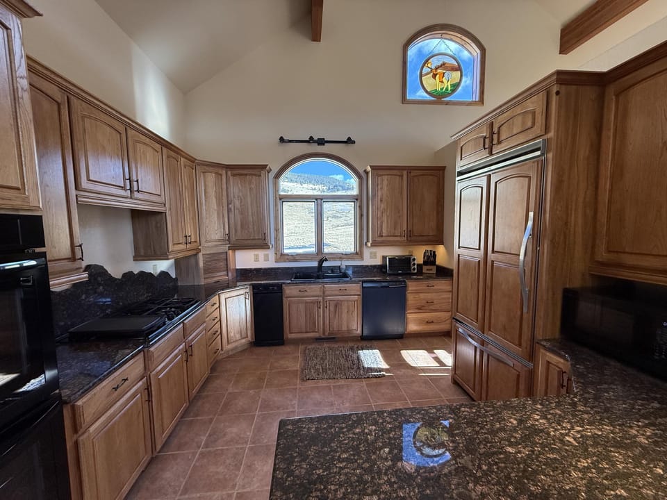 Chef's kitchen fully equipped with double oven, dishwasher, gas stove, and large refrigerator. 