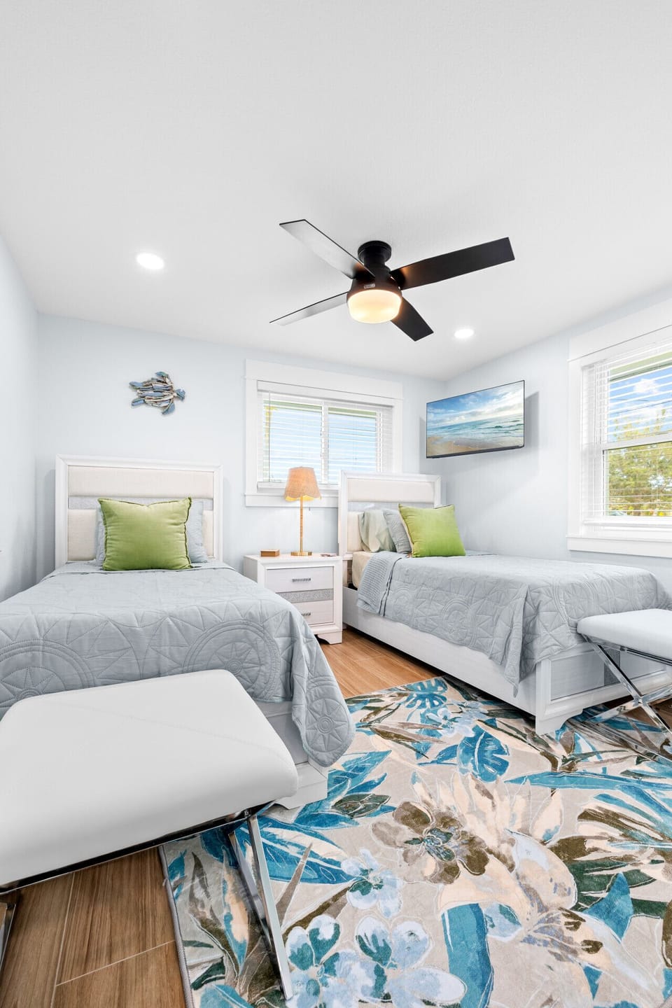 Bright twin bedroom with coastal décor, smart TV, and plenty of natural light — ideal for kids or friends.