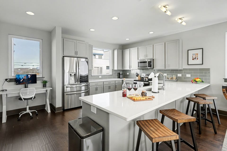 2nd Floor: Fully equipped kitchen with stainless steel appliances, ample counter space with seating for 4 guests, and a workstation with a monitor and desk chair.