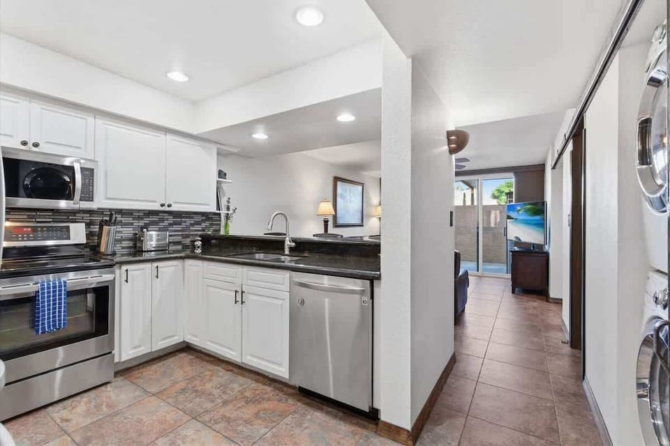Fully equipped kitchen with stainless steel appliances, bar seating for three, and a convenient laundry area with a washer and dryer.