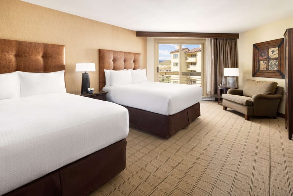 Two queen beds with mountain view and cozy sitting chair