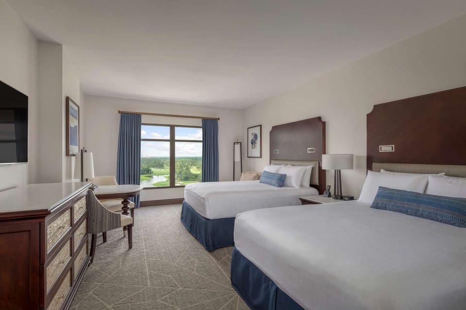 Room with two queen beds, dresser, desk, and large window view
