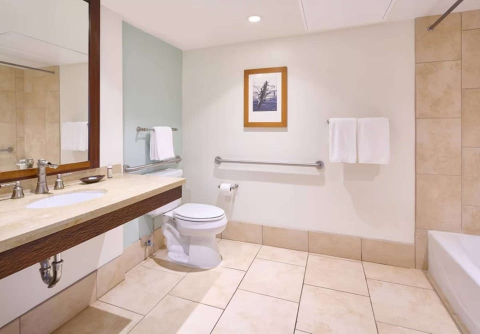 Spacious bathroom with large mirror, grab bars, and tiled floor