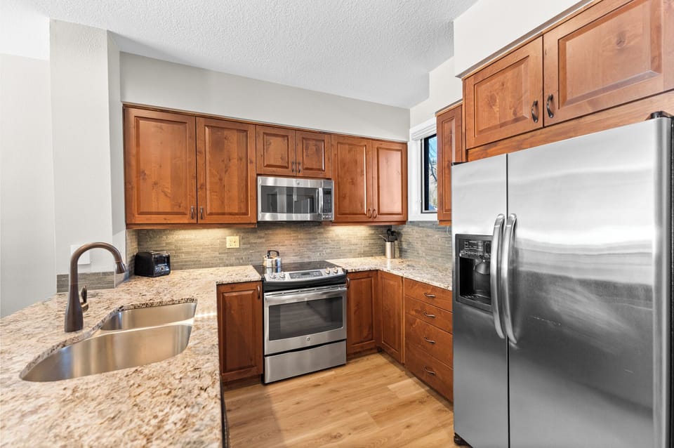 Cook your favorite meals in this fully equipped kitchen featuring granite countertops, warm wood cabinets, and stainless steel appliances.
