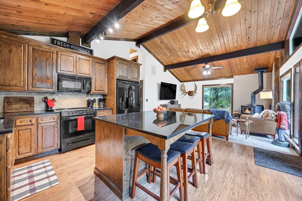 Open-concept kitchen and living space with wood ceilings—warm, inviting cabin vibes.