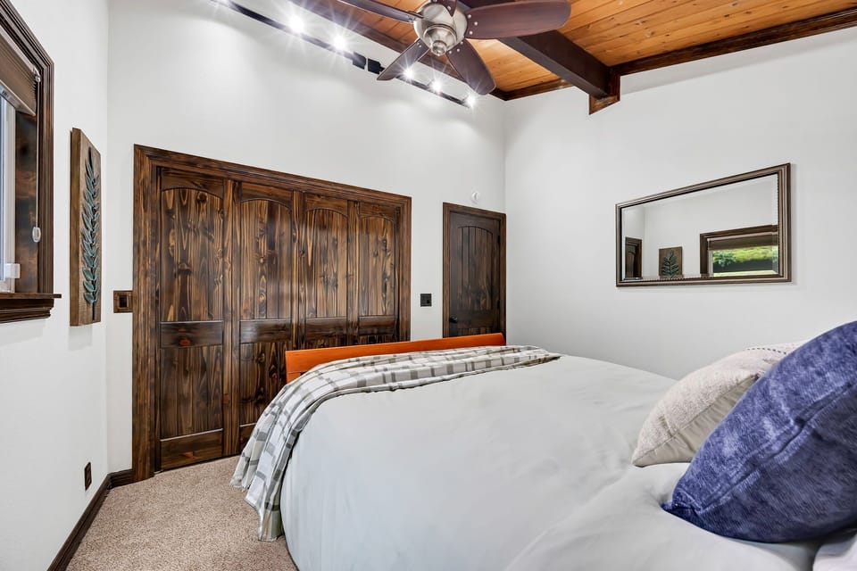 Serene bedroom retreat with rustic wood accents, bright lighting, and plush bedding—perfect for a relaxing escape.