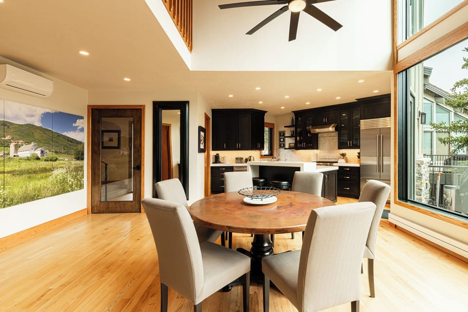 Cozy round dining setup with vaulted ceilings and open kitchen access.