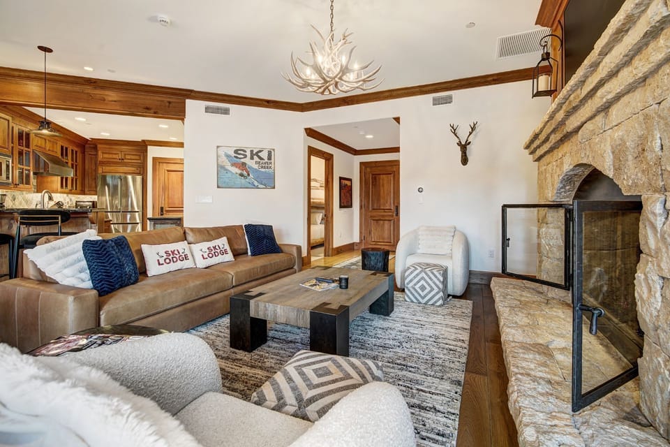 The spacious living room exudes charm, featuring beautiful wood finishes, a cozy fireplace, and uninterrupted views of the majestic mountains.