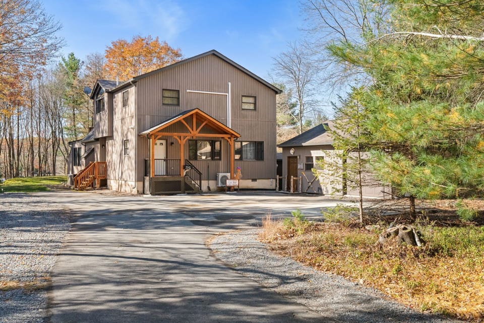Charming A-frame chalet exterior with spacious driveway parking and secluded forest surroundings