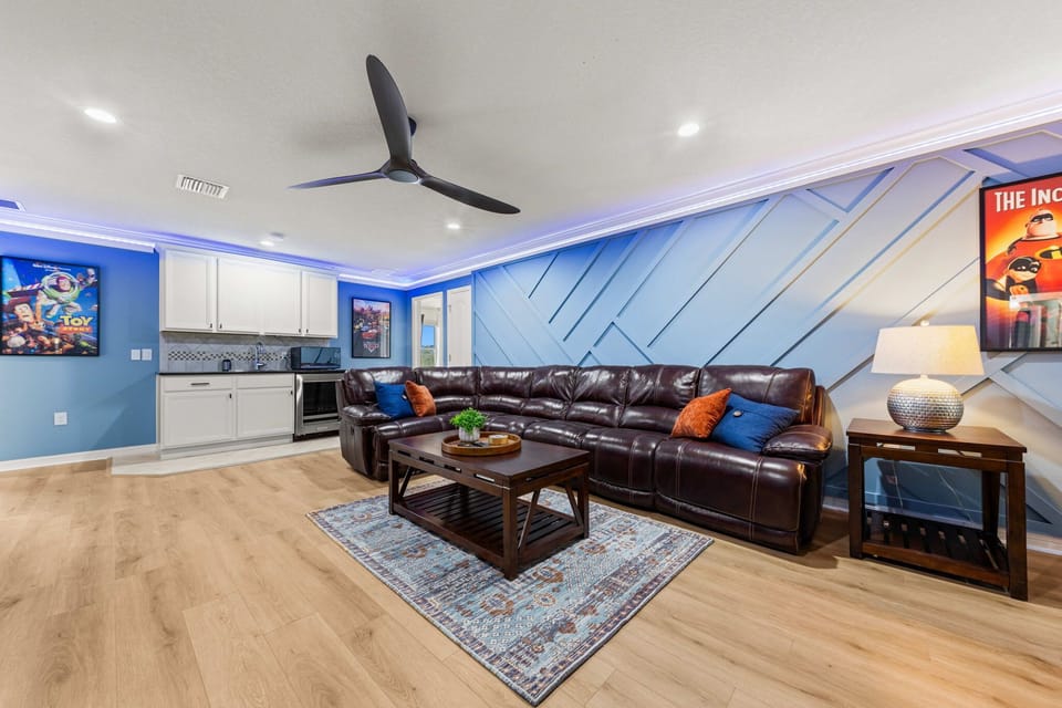 The ultimate hangout space featuring a large sectional sofa, 98" wall-mounted smart TV, Xbox gaming, LED lighting, and high-top seating.