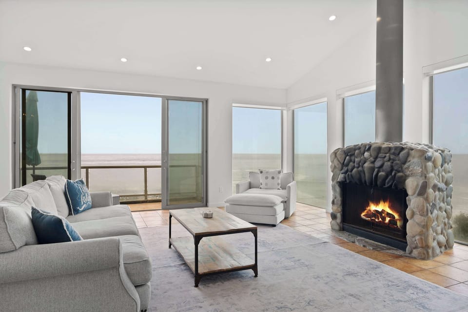 Living Room — Lit Stone Fireplace & Floor-to-Ceiling Ocean Views