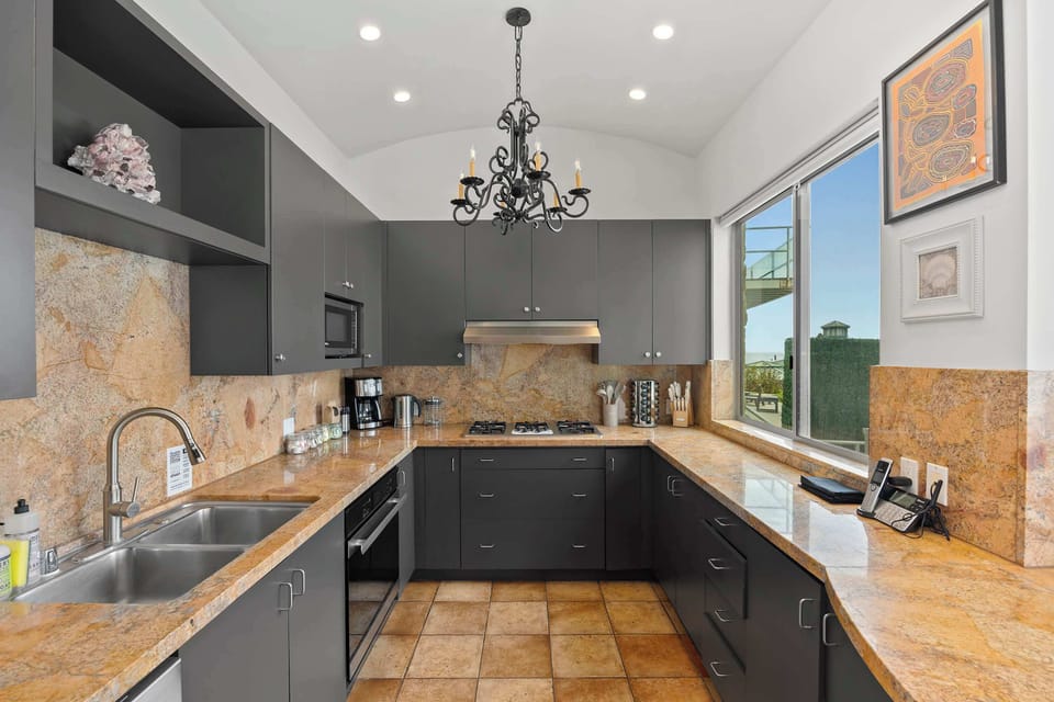 Chef's Kitchen — Dark Cabinetry, Stone Backsplash & Chandelier