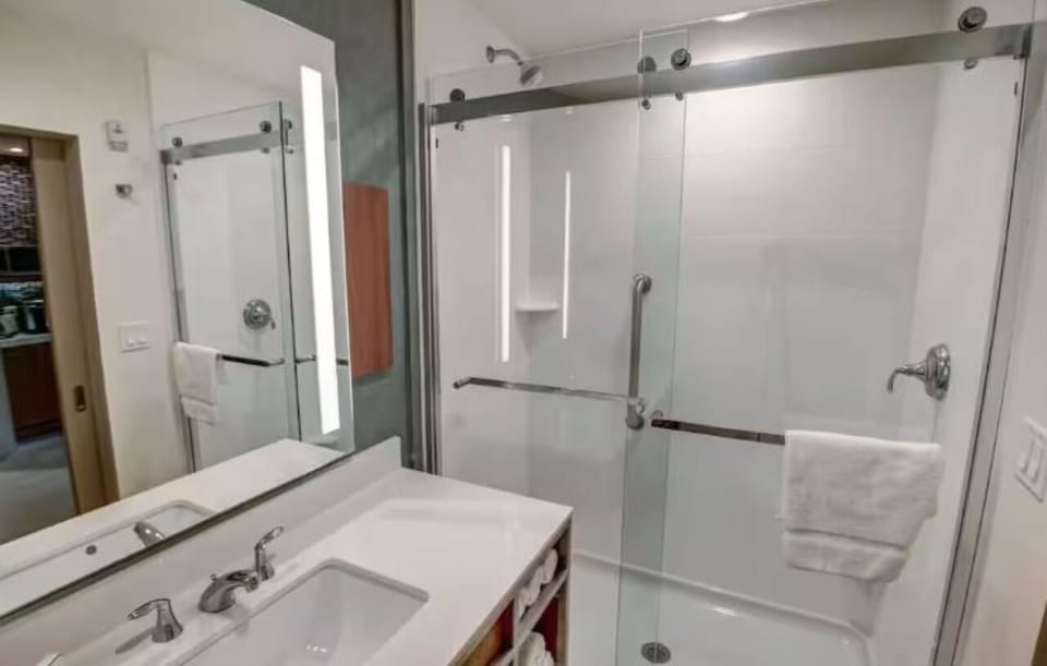 Refresh under a bright glass shower with plush towels
