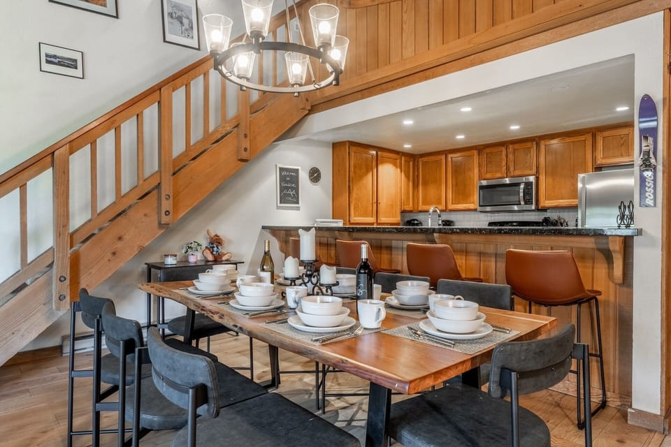 Gather around the inviting dining table where shared meals and memories await beneath warm rustic lighting. The fully-equipped kitchen is ready for culinary creations, with a loft above providing extra space to spread out and relax.