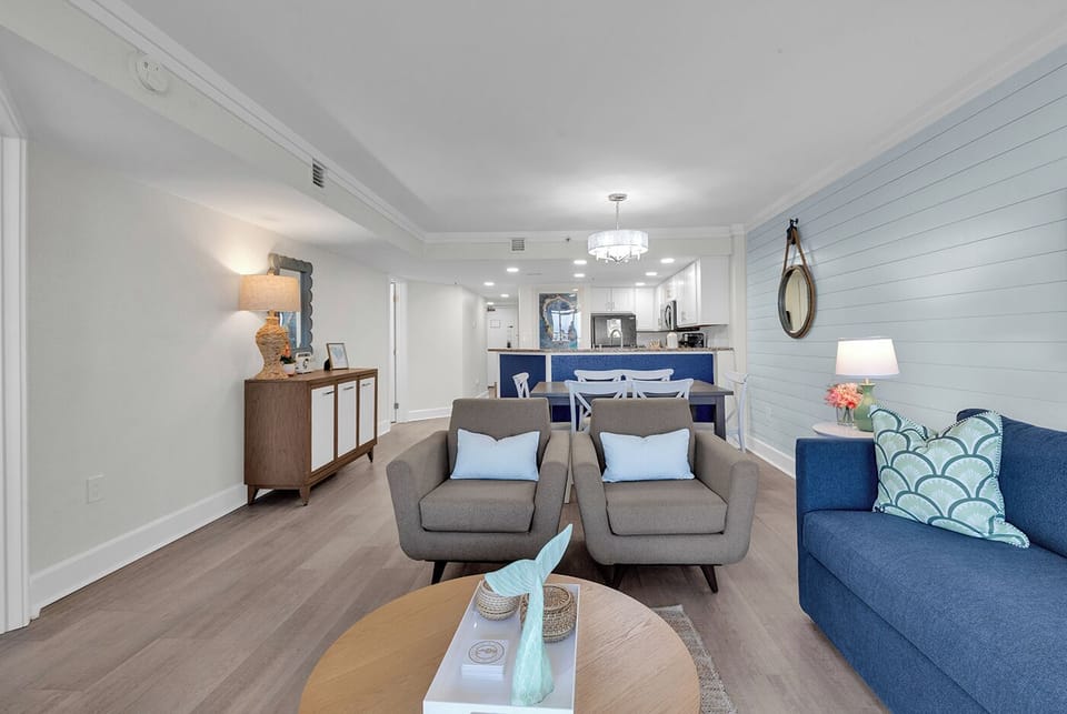 Sunny coastal living area with shiplap accent and open kitchen.