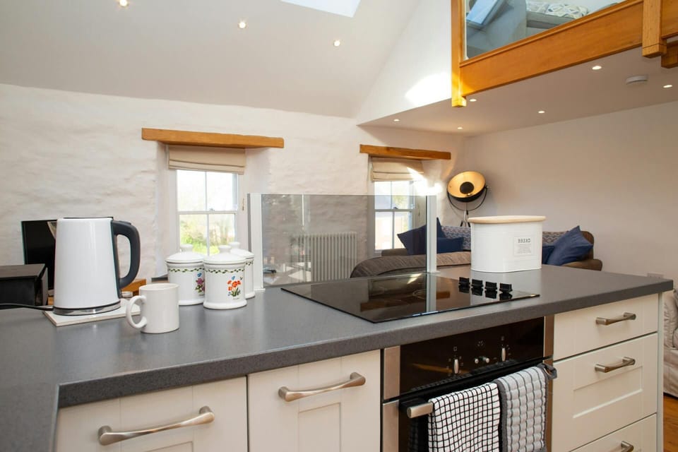Open-plan kitchen with worktop, kettle, mugs, and a mezzanine level above