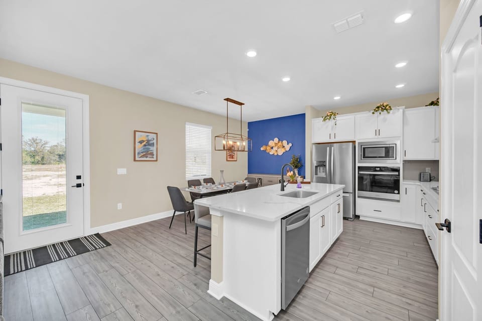Modern kitchen and dining area with a blue accent wall and stainless steel appliances