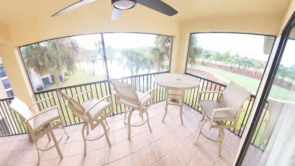 Screened balcony with seating for 4 and view of 14th hole tee box and 3r