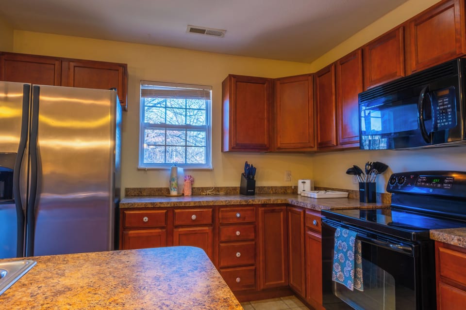 Channel your inner chef in our warm and inviting kitchen. The rich wood cabinetry and ample counter space provide a homey atmosphere where you can brew your morning coffee while looking out at the trees through the window.