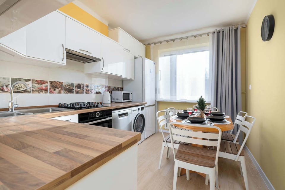 A kitchen perspective with white cabinetry, appliances, and wooden countertops. The workspace is clean and organized. Everything appears well-maintained.