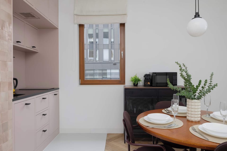 Elegant dining area with wooden table and minimalist kitchen in the background.