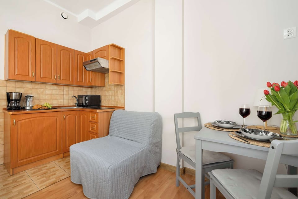 A kitchenette and seating corner with wooden cabinets, a small sofa, and a compact table arranged efficiently.