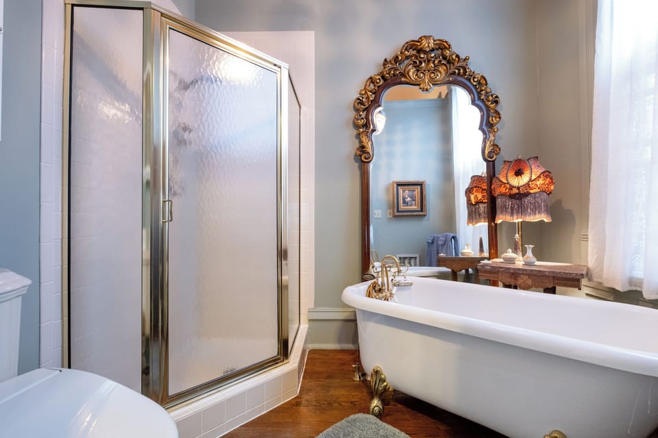 Private bathroom with clawfoot bubble bathtub, glass-enclosed shower, Japanese-style bidet toilet, and elegant vintage-style fixtures