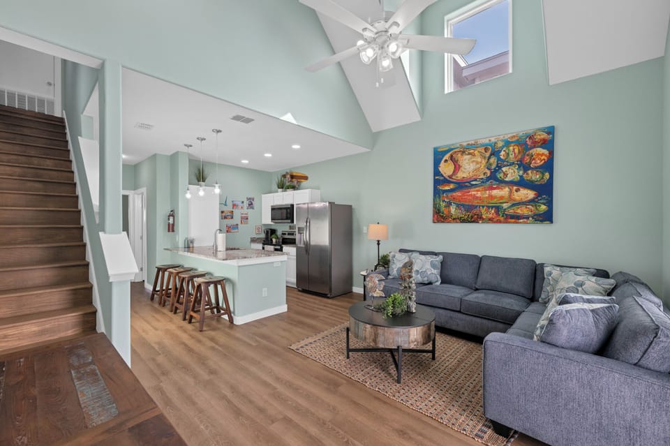 Relax in your bright open-concept living space with soaring vaulted ceilings, modern kitchen, and cozy sectional sofa perfect for unwinding.