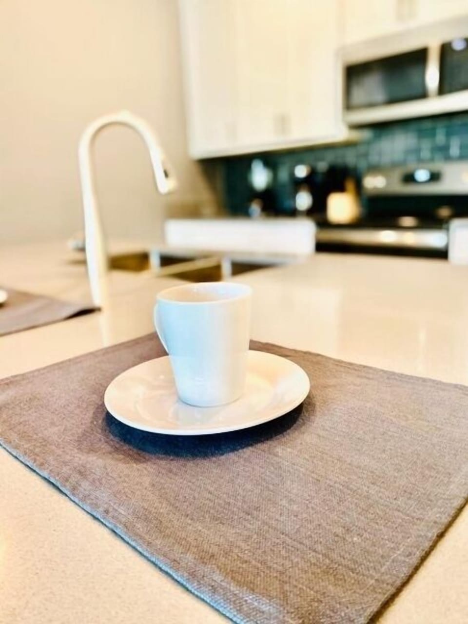 Sip your morning coffee in this sleek kitchen with modern appliances and pristine countertops perfect for cooking.