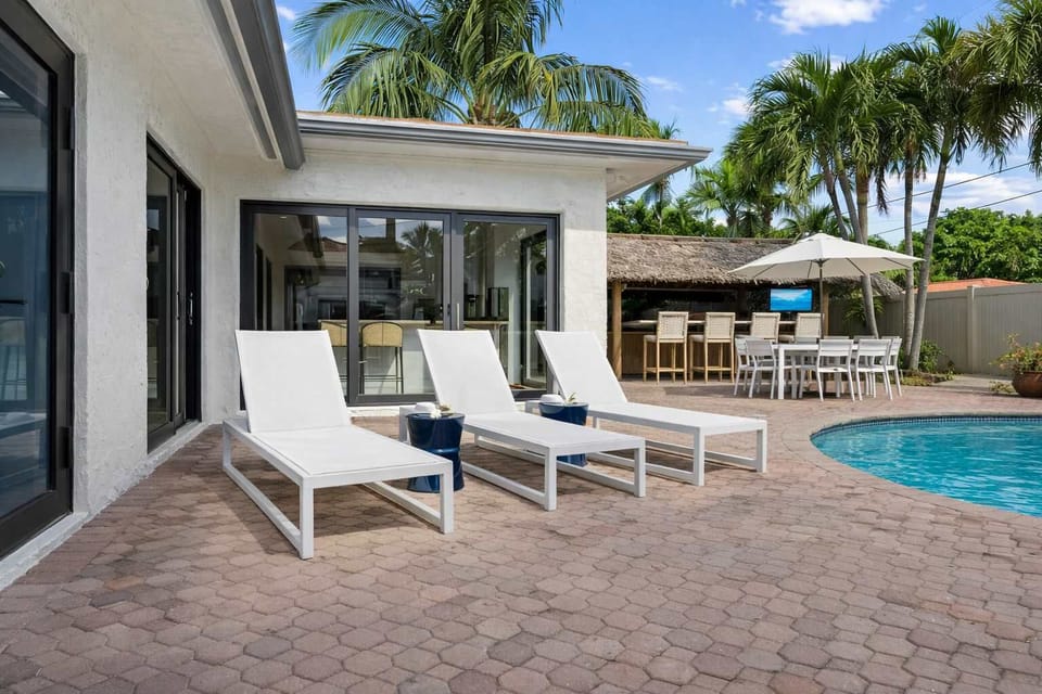 Shaded lounge area with white chairs overlooking pool