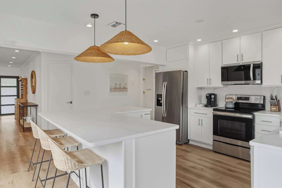 Chef's kitchen with white cabinetry and woven pendant lights