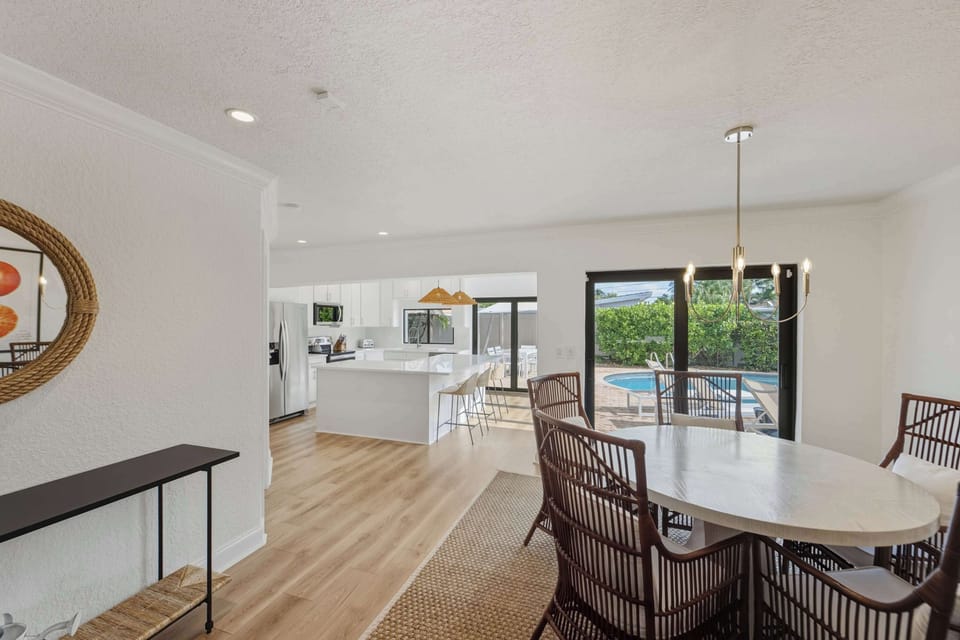 Dining area with oval table overlooking pool and kitchen