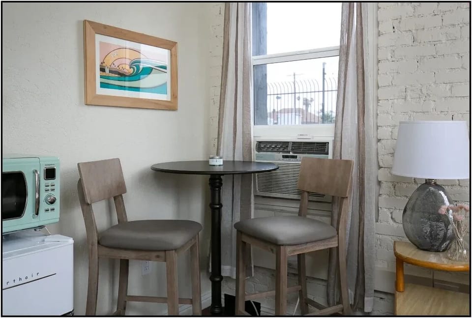 Your cozy dining nook features a charming bistro table for two, perfect for morning coffee or intimate meals with exposed brick walls adding character.