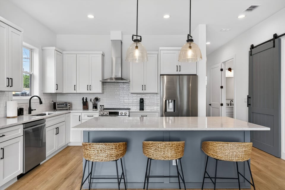 A modern kitchen with sleek white cabinets and stylish pendant lighting creates an inviting culinary space.