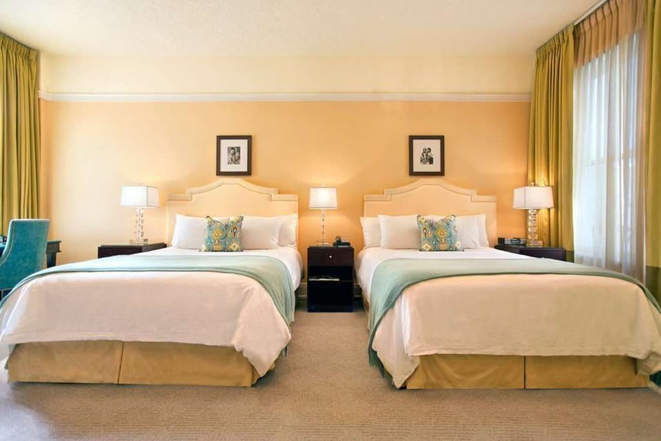 Enjoy a restful night in our spacious room with two queen beds, featuring elegant decor and modern amenities.