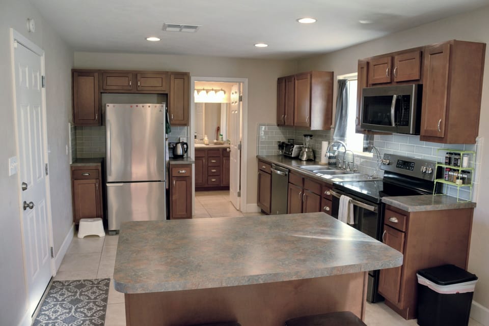 Kitchen island with 2 bar stools. Bathroom and laundry room in background.