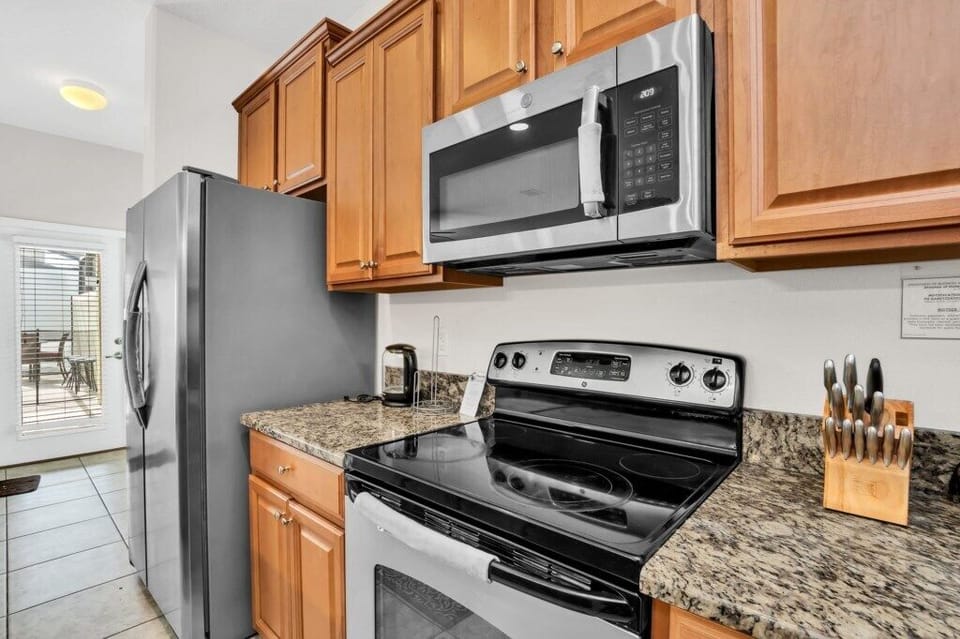 A kitchen view highlighting wood cabinetry, granite counters, and modern appliances.