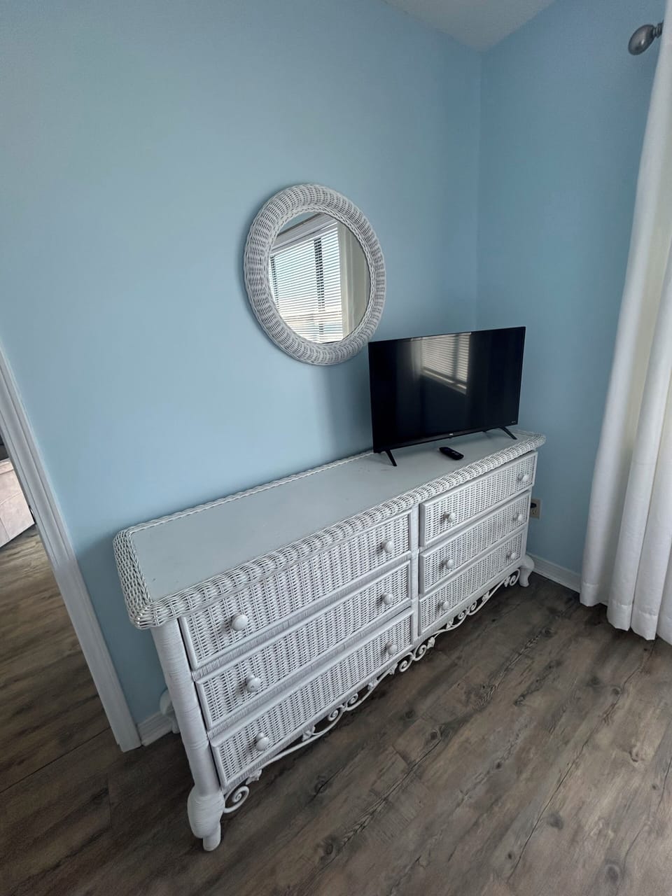Bright coastal nook with TV, round mirror & ample dresser storage