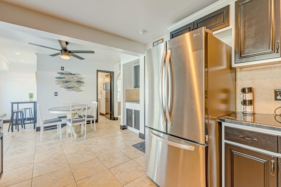 The kitchen features all stainless steel appliances: fridge, stove, oven, microwave, dishwasher, toaster, and blender with full cooking utensils and dishware.