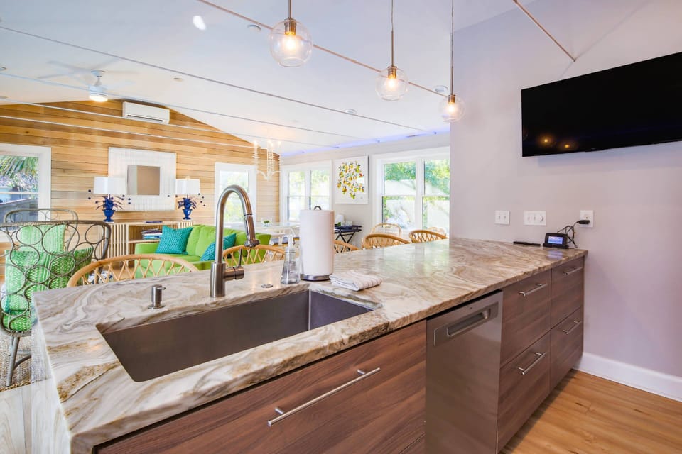 The kitchen features a dishwasher, deep sink, drawer-style cabinets and a wall-mounted TV.