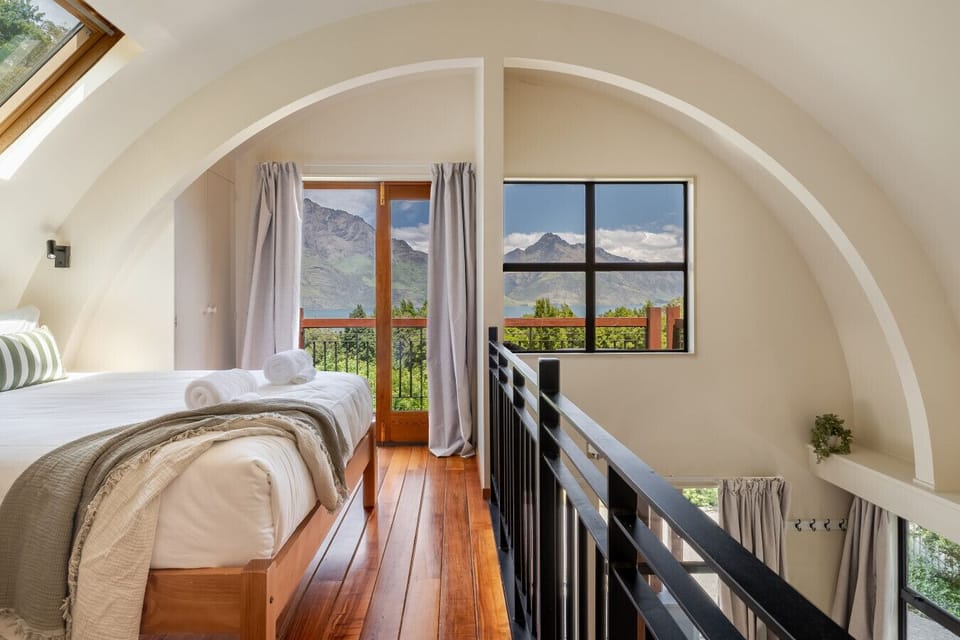 Loft bedroom with arched ceiling and views toward the mountains and lake